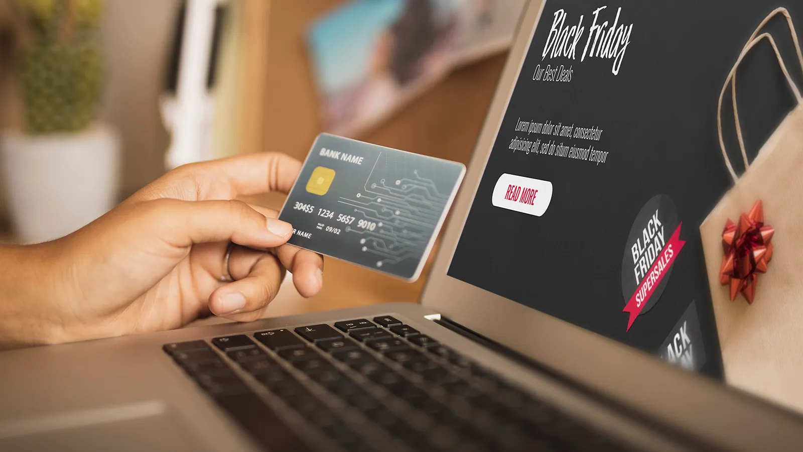 Mão segurando cartão de crédito em frente a notebook com ofertas de Black Friday para finalizar compra no checkout